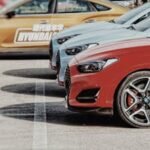 Close-up of stylish sports cars parked in a row outdoors at daytime.